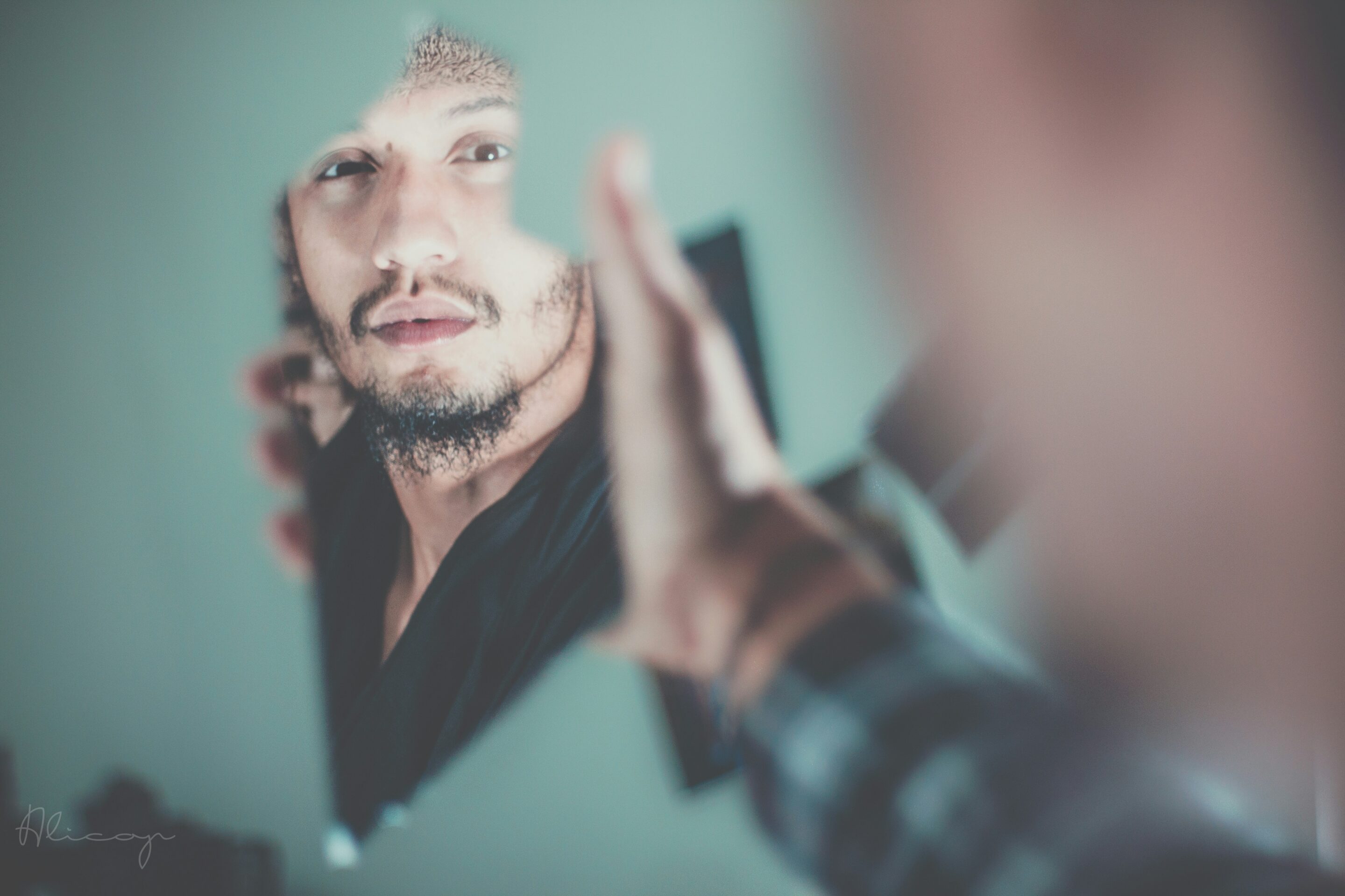Uomo che osserva il proprio riflesso frammentato, immagine simbolica dell’alessitimia e della difficoltà nel riconoscere le proprie emozioni.