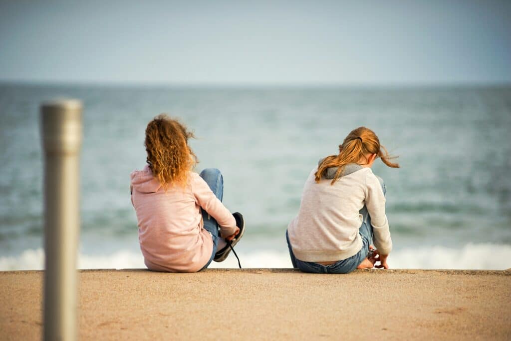 Due persone sedute distanti tra loro davanti al mare, immagine simbolica delle dinamiche relazionali e della distanza emotiva che può accompagnare l’ansia.