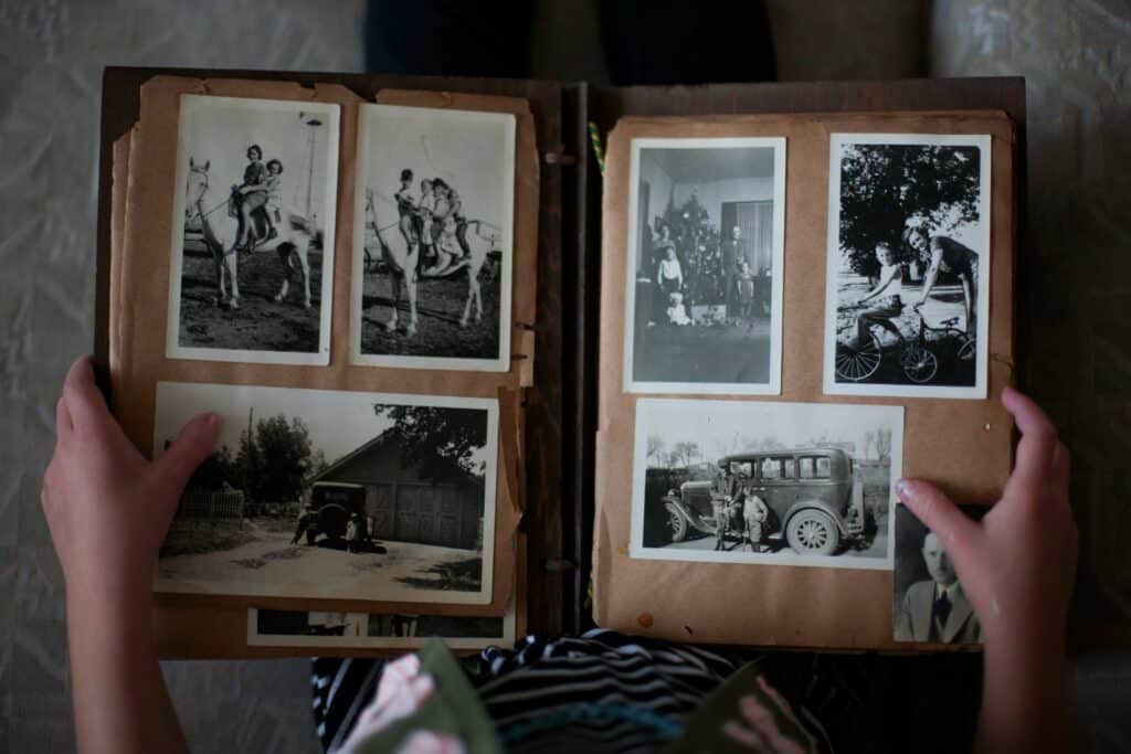Una persona sfoglia un vecchio album con fotografie di famiglia, immagine legata alla memoria e alla storia tra generazioni.