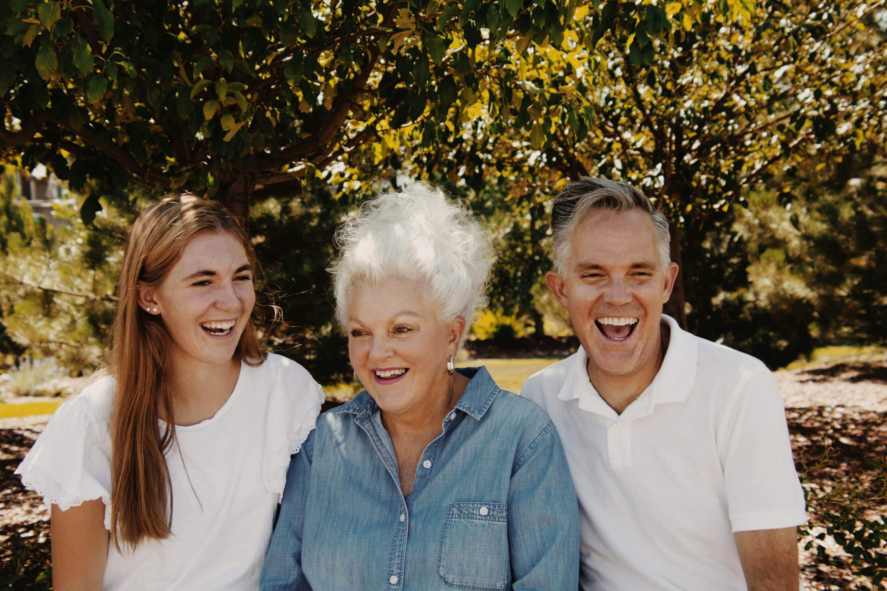 Tre persone di età diverse sorridono insieme all’aperto, immagine simbolica delle relazioni tra generazioni.