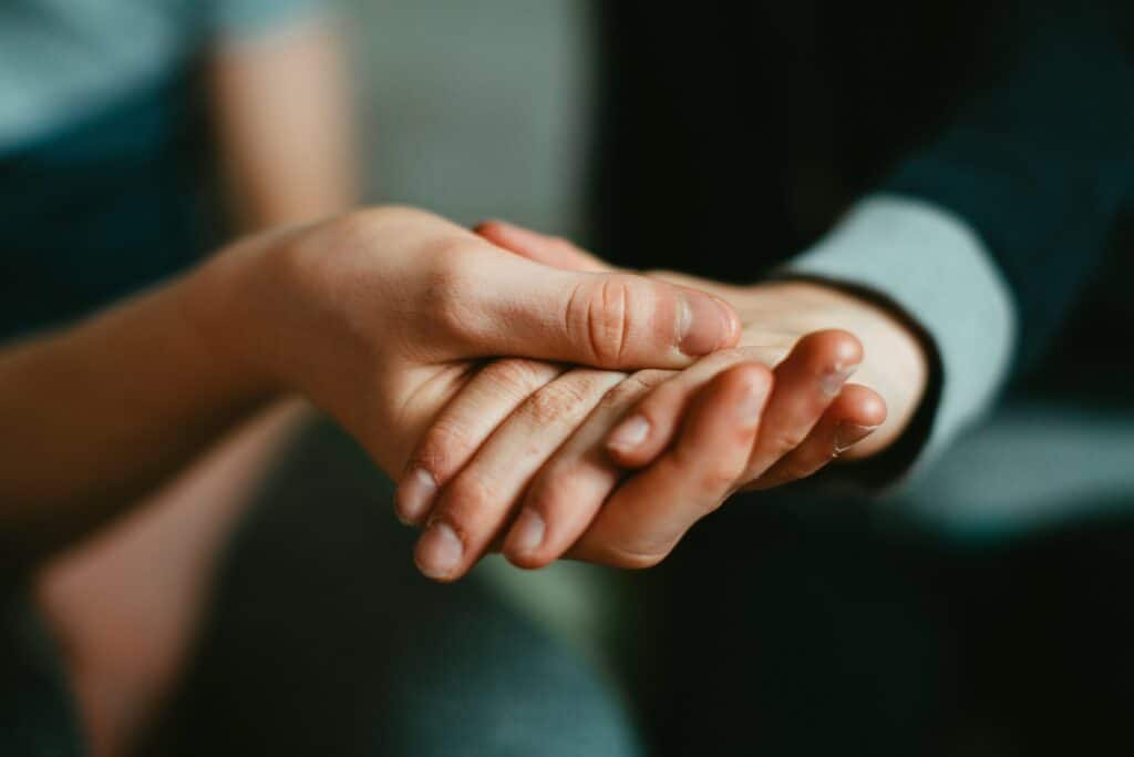 Una mano appoggiata sull’altra in un gesto di sostegno, immagine legata alla relazione e alla coregolazione in psicoterapia.