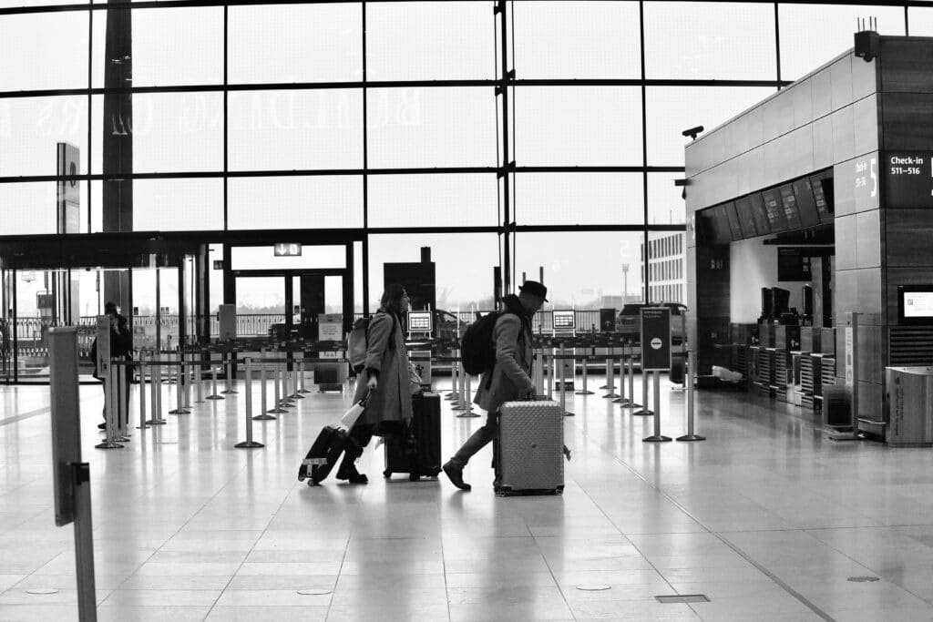 Persone con bagagli camminano in aeroporto durante il rientro dalle vacanze e la graduale ripresa della routine quotidiana.