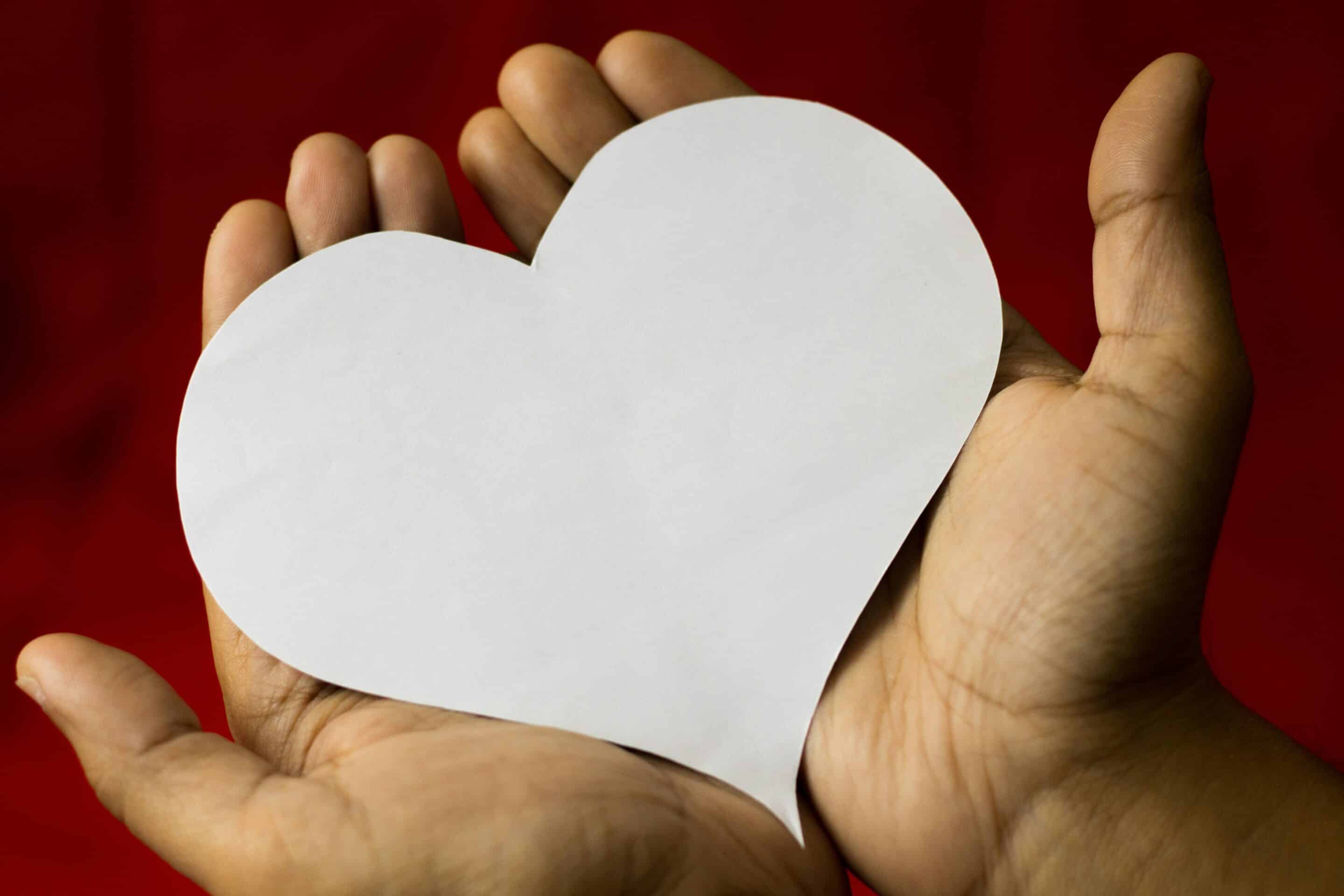 Una persona tiene tra le mani un cuore di carta, immagine legata all’autocompassione e alla gentilezza verso se stessi.