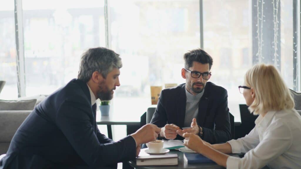 Tre persone dialogano attorno a un tavolo, immagine che richiama il contesto sociale in cui opera lo psicologo.