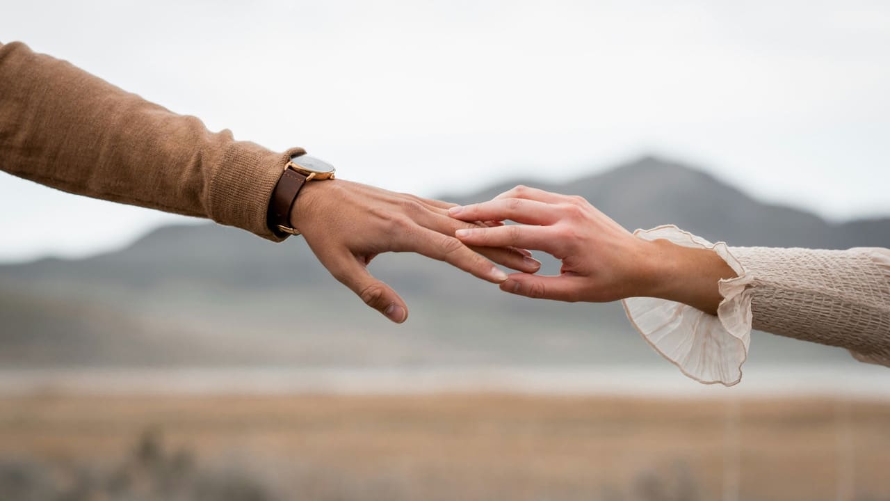 Due persone si sfiorano le mani all'aperto, simbolo del legame tra corpo, emozioni e relazioni nella psicosomatica.