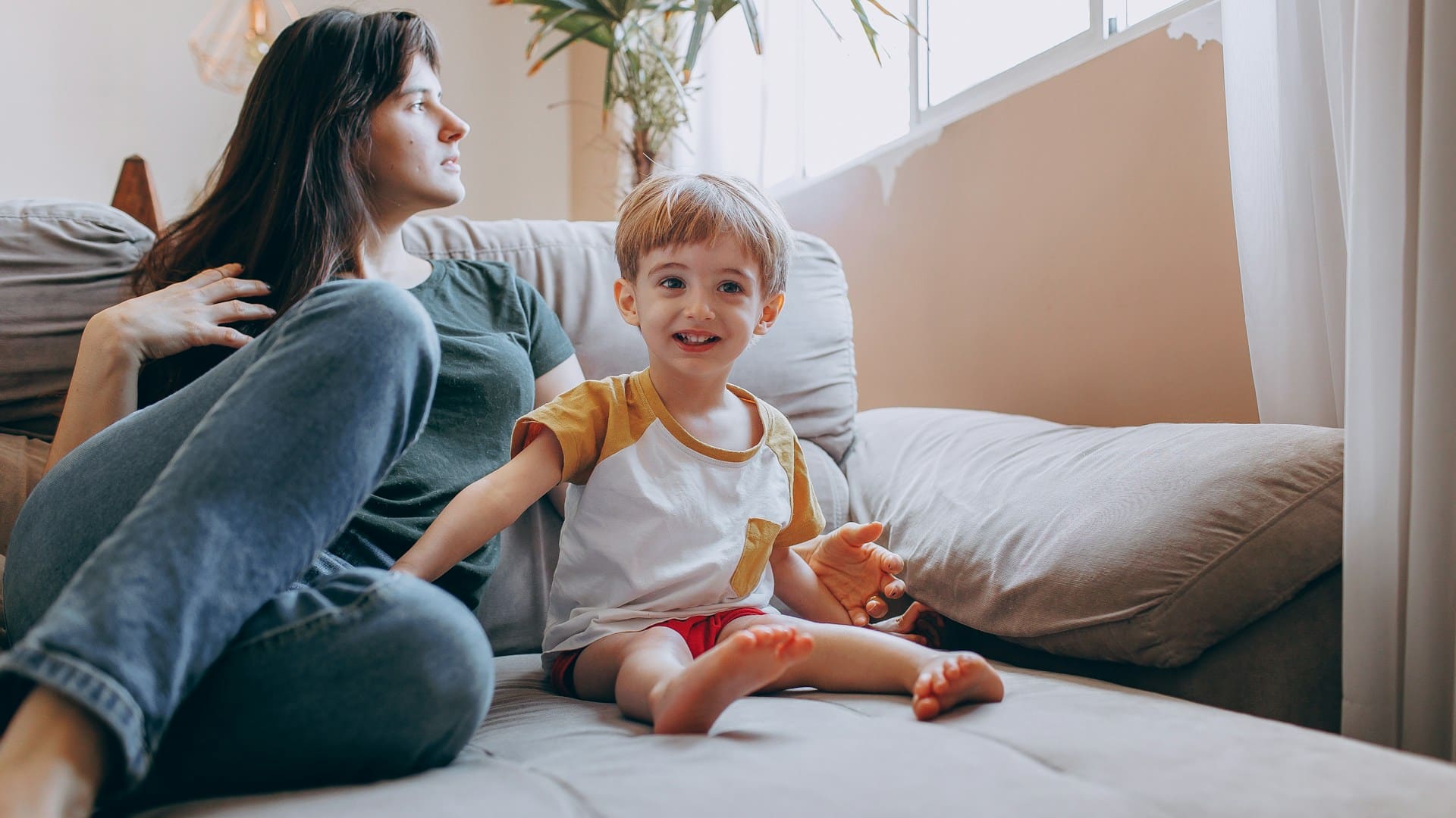 Regolazione emotiva dei genitori: madre e bambino seduti insieme sul divano.